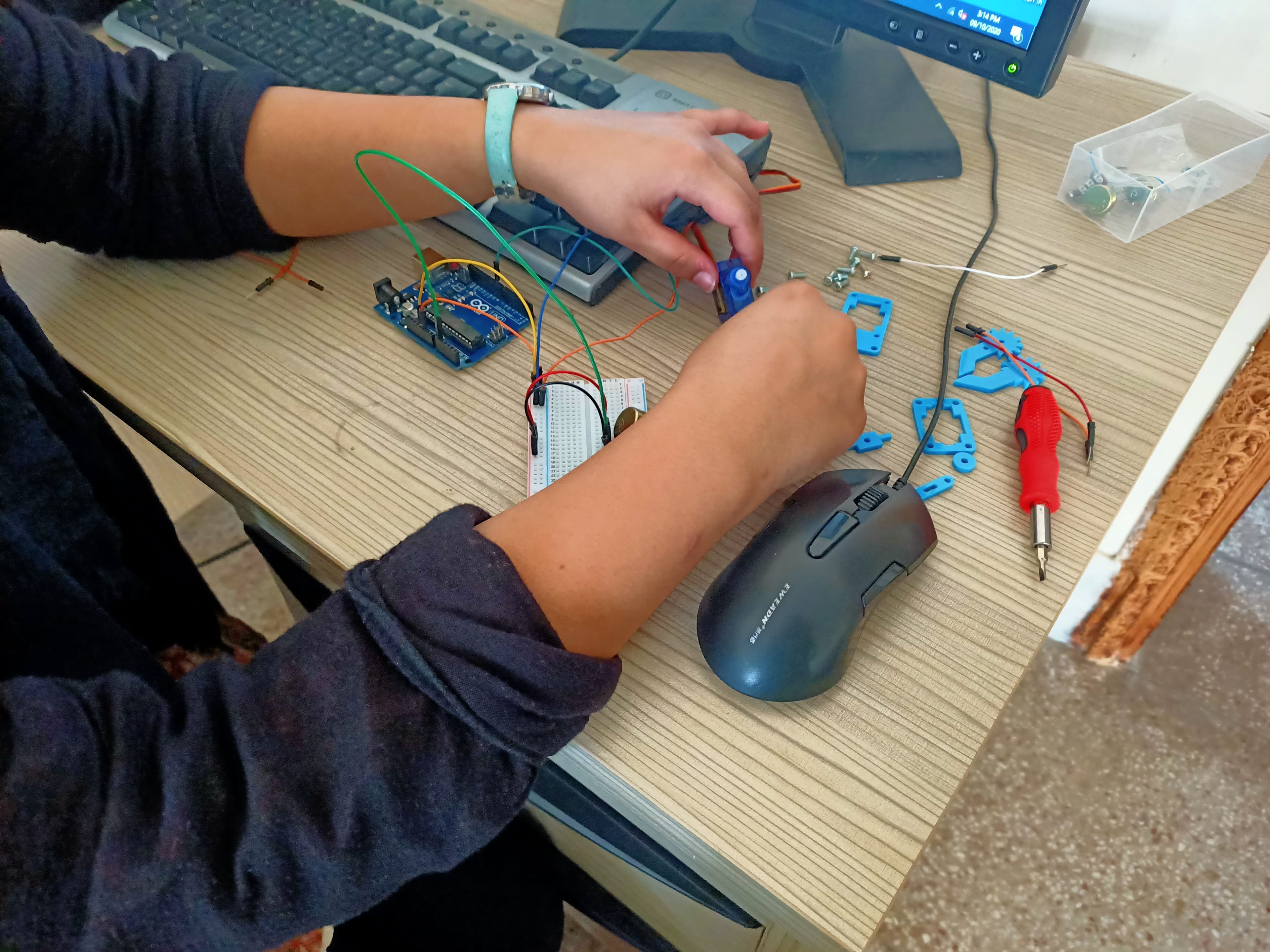 A student's hands wiring an Arduino breadboard circuit