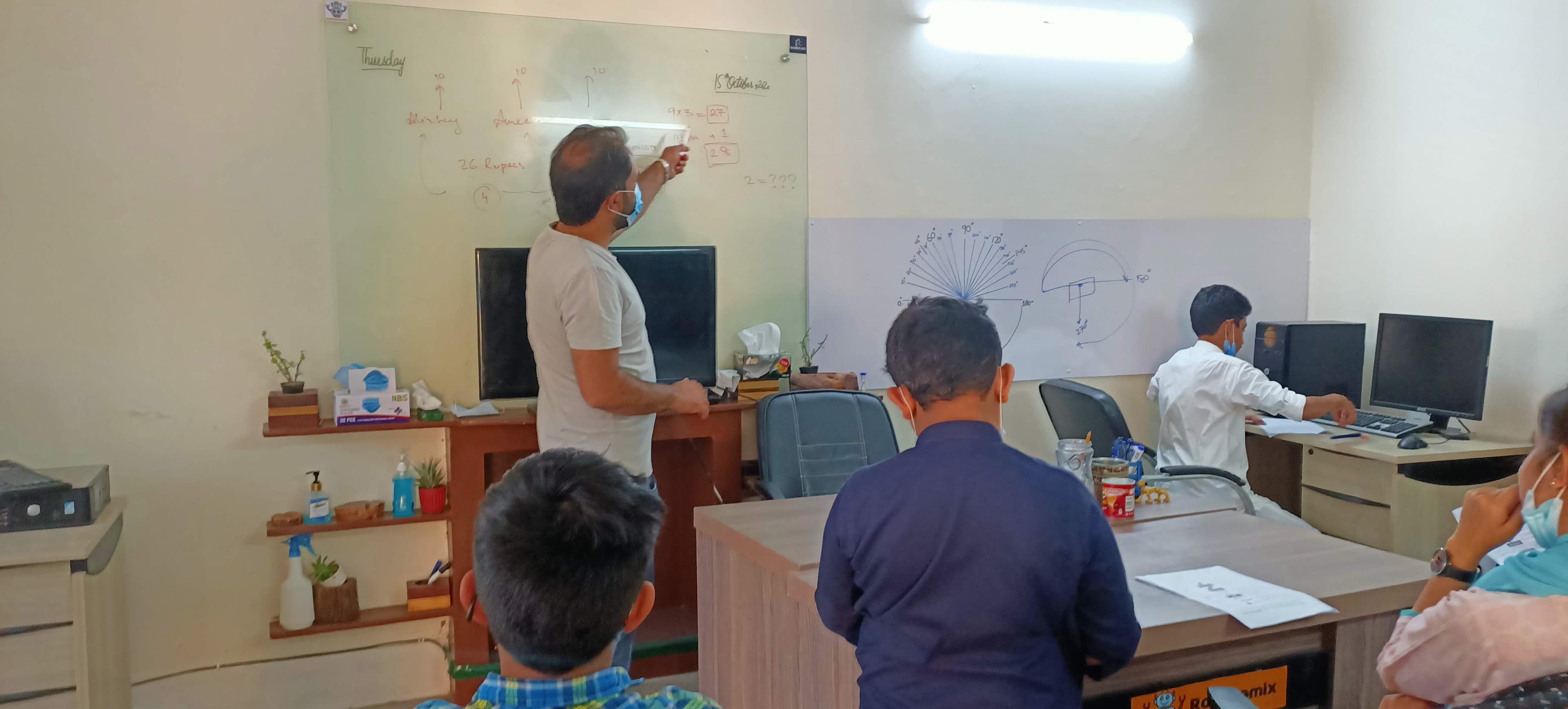 An instructor working through a problem at the whiteboard with students