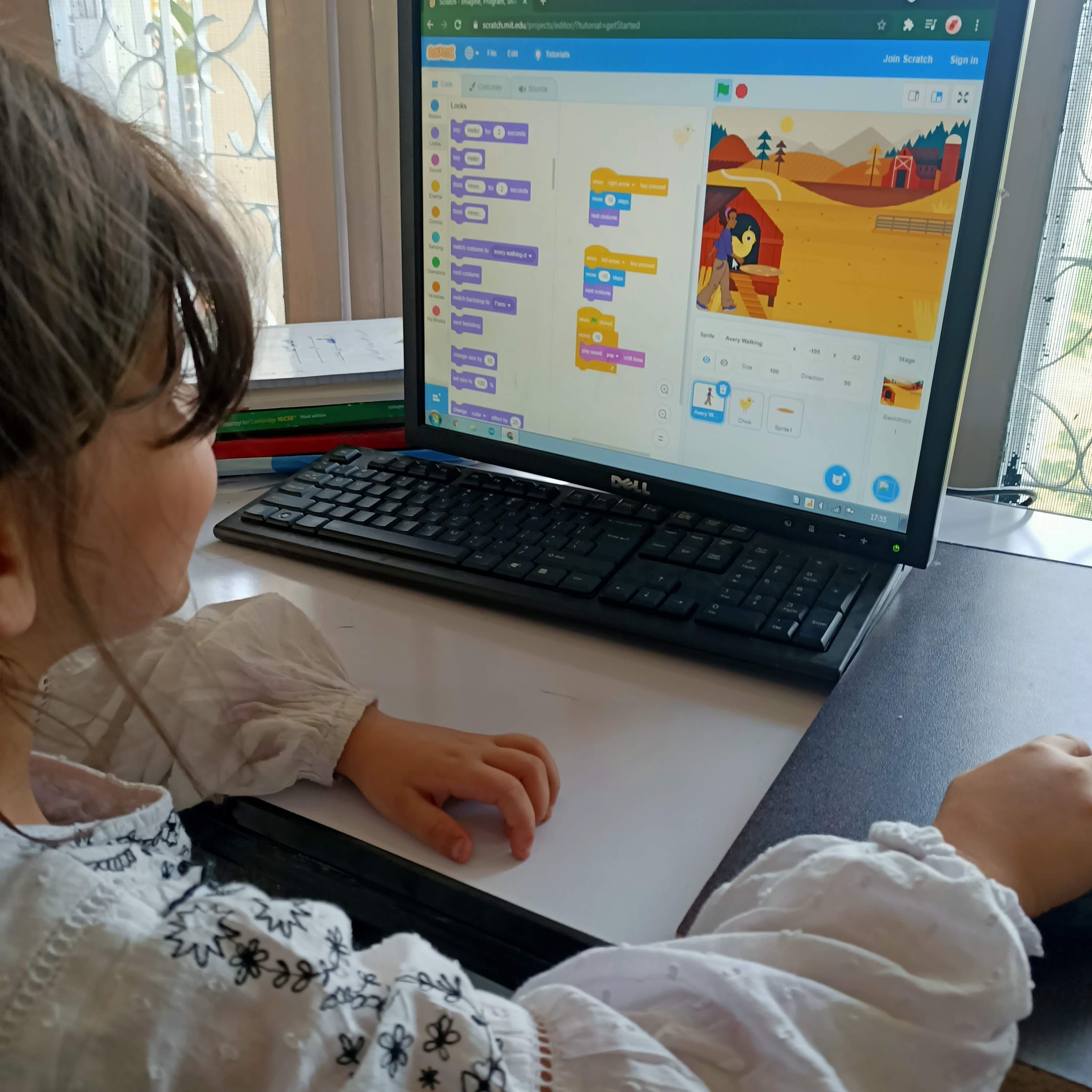 A young student building a project in Scratch on screen
